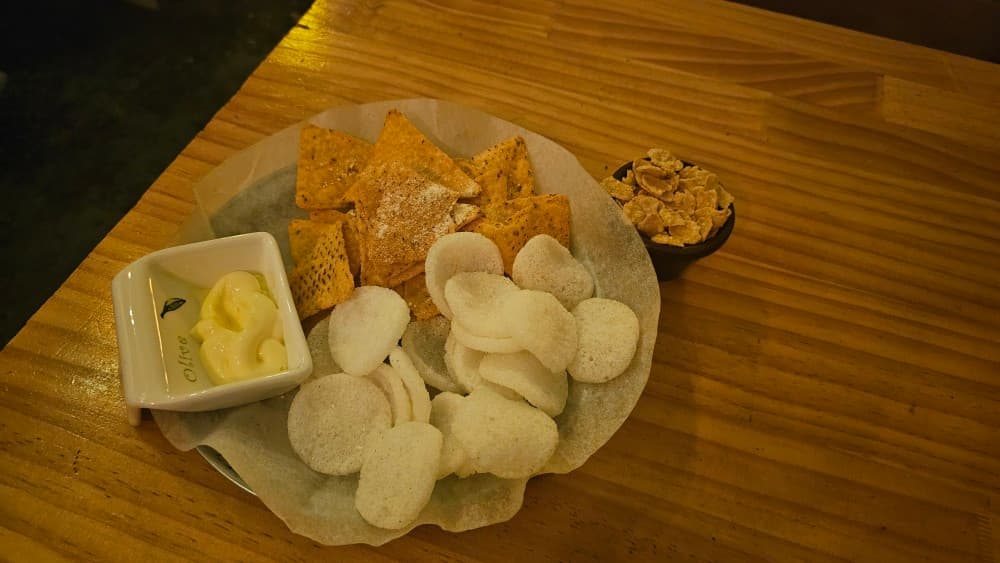 또로롱호프의 나초와 새우칩, 소스가 담긴 기본 안주 세트. 아늑한 나무 테이블에서 가볍게 혼술하기 좋은 구성입니다.