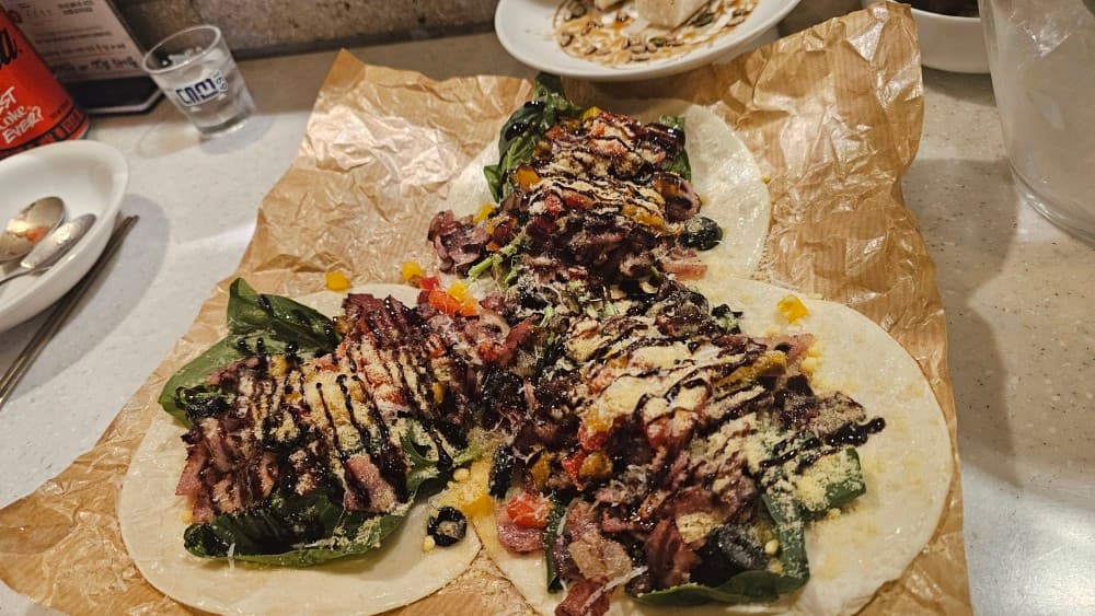 전포동 선술집 엣헴의 바 테이블 위 소고기와 채소가 듬뿍 담긴 타코 안주, 혼술하기 좋은 분위기