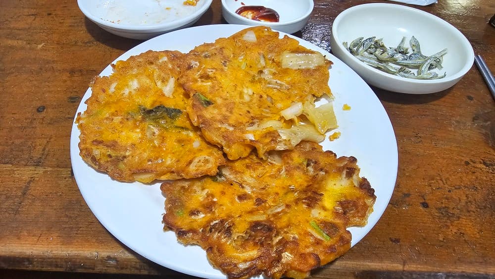 동래 오딧세이 포차의 바삭한 김치전과 멸치 안주, 혼술하기 좋은 아늑한 나무 테이블 분위기