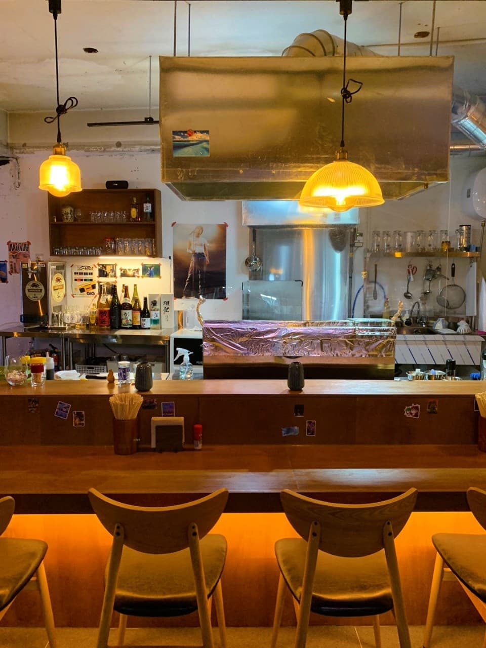 서울특별시 동대문구 천호대로87길 13-3에 위치한 야키토리 지도리 내부. 따뜻한 조명과 긴 바 테이블이 있어 혼술이나 혼밥하기 좋습니다. 주방 선반에 사케 병과 포스터가 진열된 일본 감성 술집 분위기입니다.