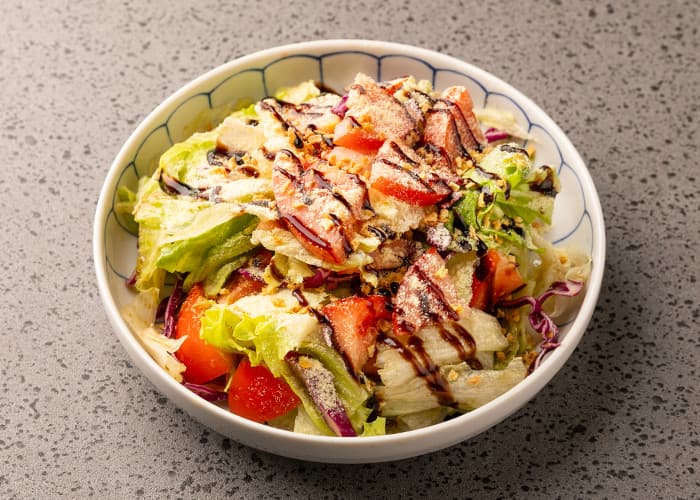 회색 석재 질감 테이블 위 양상추와 토마토, 발사믹 드레싱과 치즈 가루를 곁들인 1인용 샐러드 볼