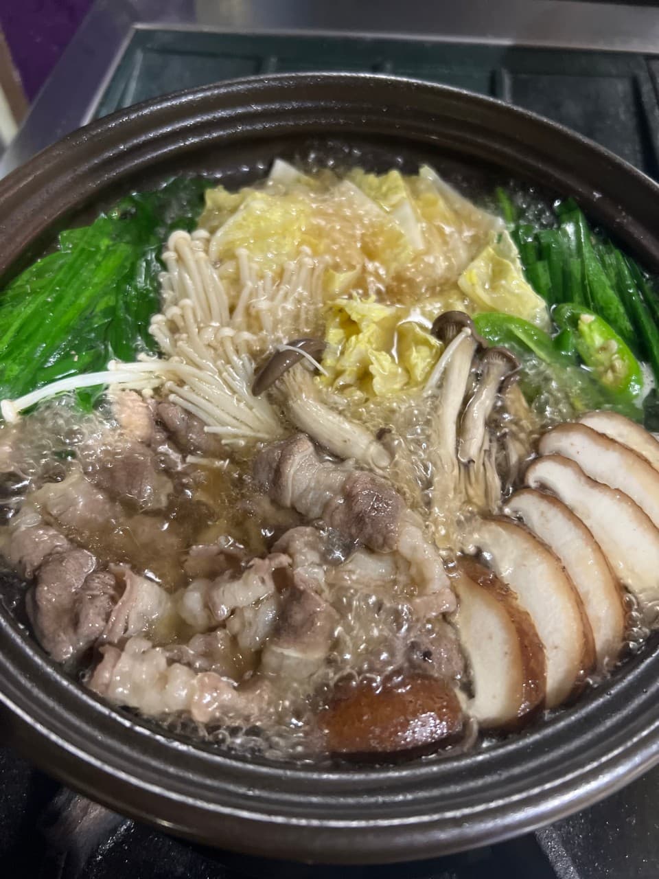 갈색 전골 냄비 안에서 끓고 있는 소고기와 표고버섯, 팽이버섯, 배추가 어우러진 1인용 요리