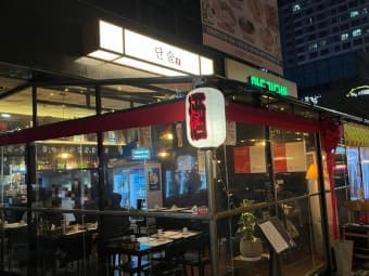 붉은 글씨가 적힌 흰색 제등이 켜진 통유리 외관과 내부 조명 아래 조밀하게 배치된 1인용 테이블 좌석