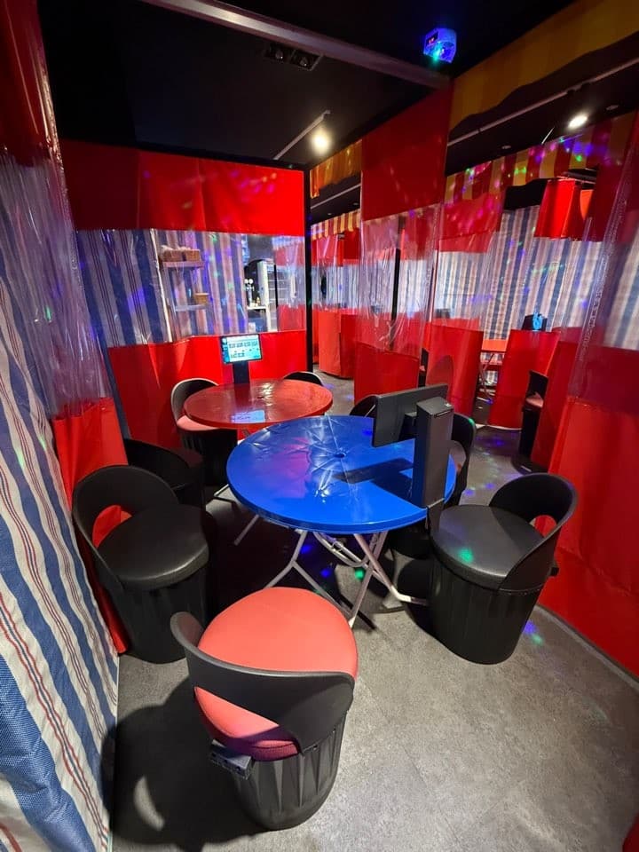 빨간 천막과 가림막으로 구분된 독립형 칸막이 좌석. 원형 테이블 위 주문용 태블릿과 여러 색의 조명이 비치는 실내 바닥