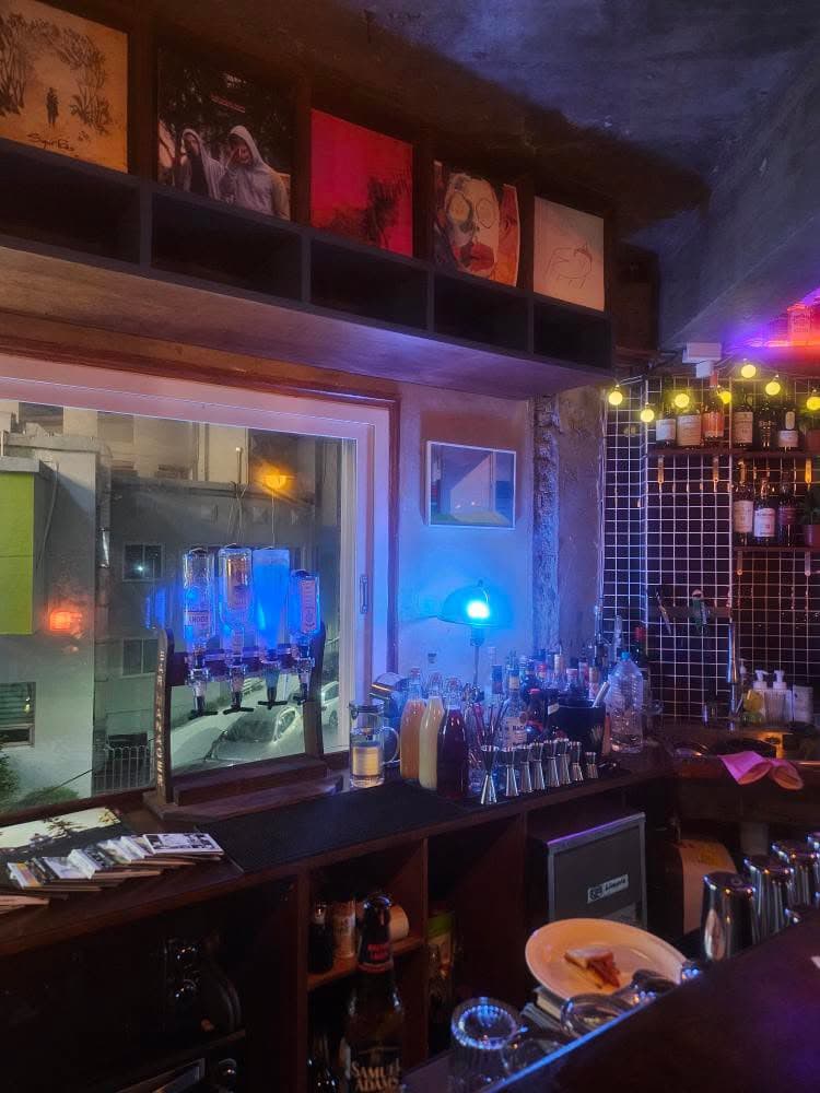 부산광역시 부산진구 페일블루닷 전포 바(Bar)의 푸른 조명이 비치는 1인 다찌석. 상단 선반의 LP 음반들과 창가에 진열된 다양한 술병이 조화를 이루는 혼술 현장.