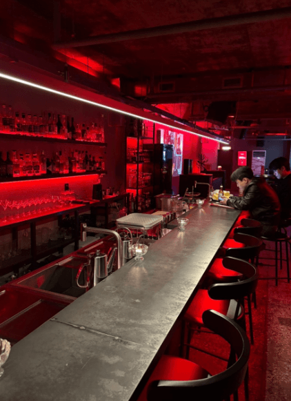 부산광역시 동구 체리베이스먼트 맥주 호프 - 붉은 네온 조명이 비치는 긴 다찌석과 벽면 선반의 술병들이 어우러진 1인 혼술 상황.