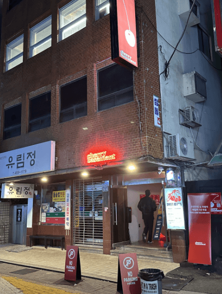 부산광역시 동구 체리베이스먼트 맥주 호프. 붉은 네온 조명 아래 지하로 들어가는 1인 손님과 매장 앞 입간판. 다찌석이 마련되어 혼술 하기 적합한 지하 매장 입구 전경.