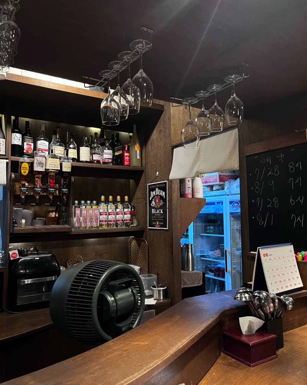 부산광역시 중구 이자카야 도코로 남포동본점의 다찌석. 주류 선반과 와인잔이 걸린 나무 카운터에서 혼술을 즐기는 1인석 상황.