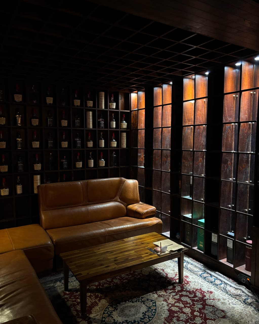 부산광역시 중구 맥주,호프 풍악 - 포인트 조명 아래 가죽 소파와 위스키가 진열된 목재 선반이 있는 1인 혼술 공간