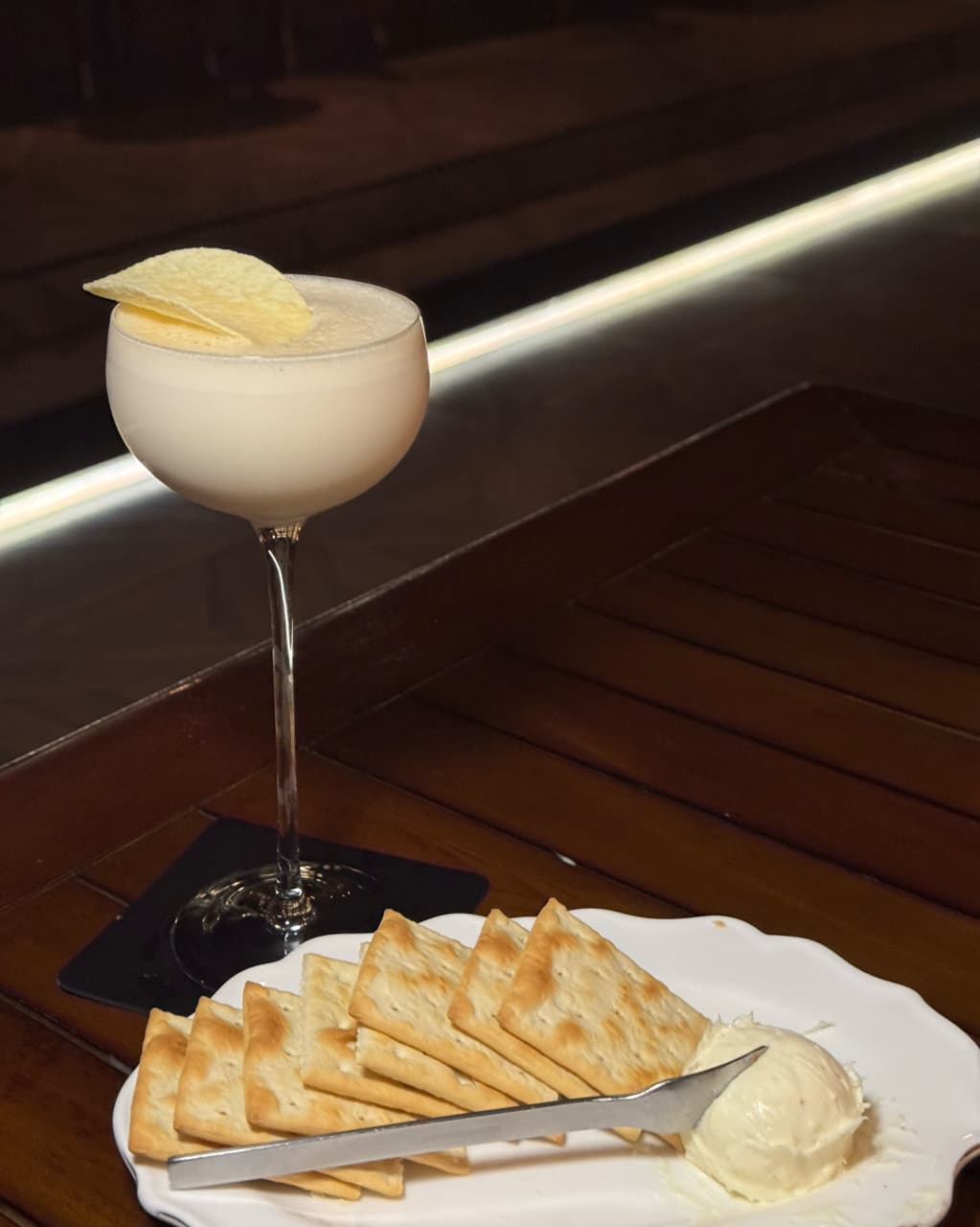 서울특별시 송파구 바 다빈치 잠실 바(Bar) 다찌석 1인 혼술 상황. 거품 가득한 칵테일과 크래커, 크림치즈가 차려진 목재 테이블 위 직선 조명.