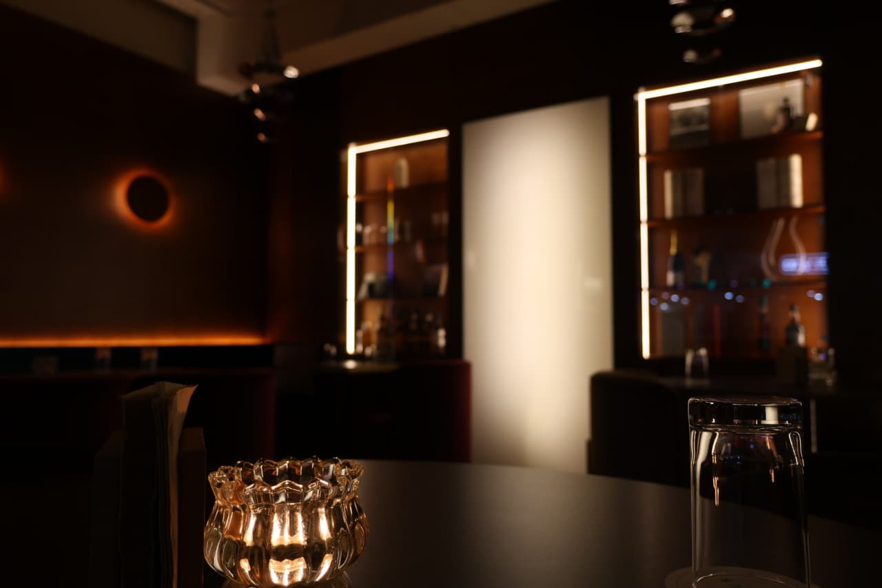 경상남도 진주시 바(Bar) 슈럽 진주의 어두운 실내. 테이블 위 촛불 조명과 유리잔, 간접 조명이 비치는 진열장 앞 1인 다찌석에서 즐기는 혼술 상황.