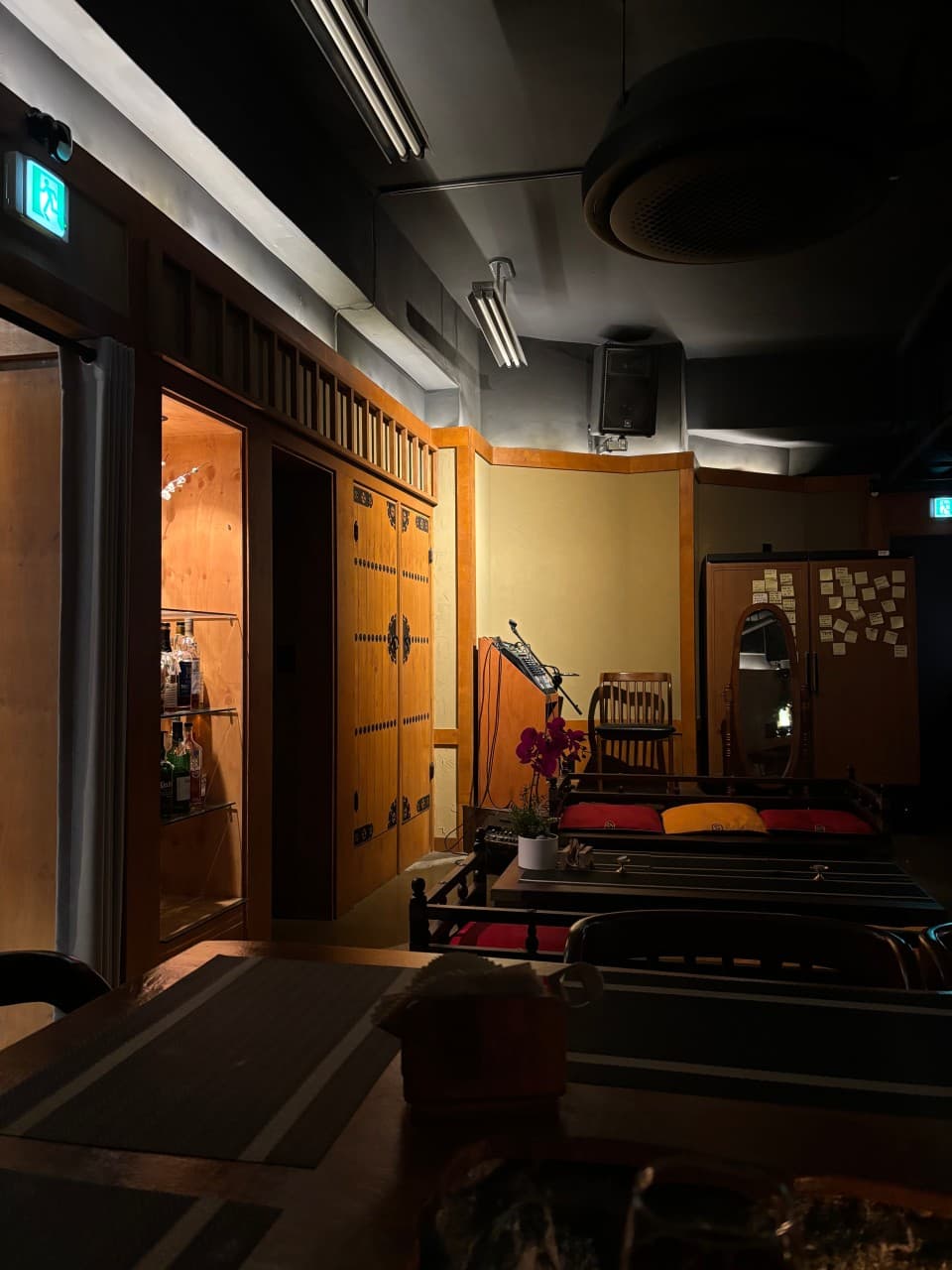 서울특별시 송파구 선율의밤 잠실방이점 바(Bar) 내부. 노란 조명이 비치는 목재 인테리어와 1인 다찌석. 혼술 상황에 적합한 술병 진열장과 오디오 장비가 배치된 공간.