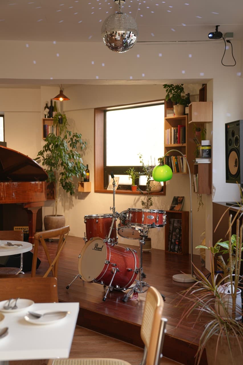 서울특별시 송파구 요리주점 디에스티클럽 석촌. 미러볼 조명과 드럼 세트가 있는 실내 무대 옆으로 1인 혼술을 위한 테이블과 의자가 배치된 모습.