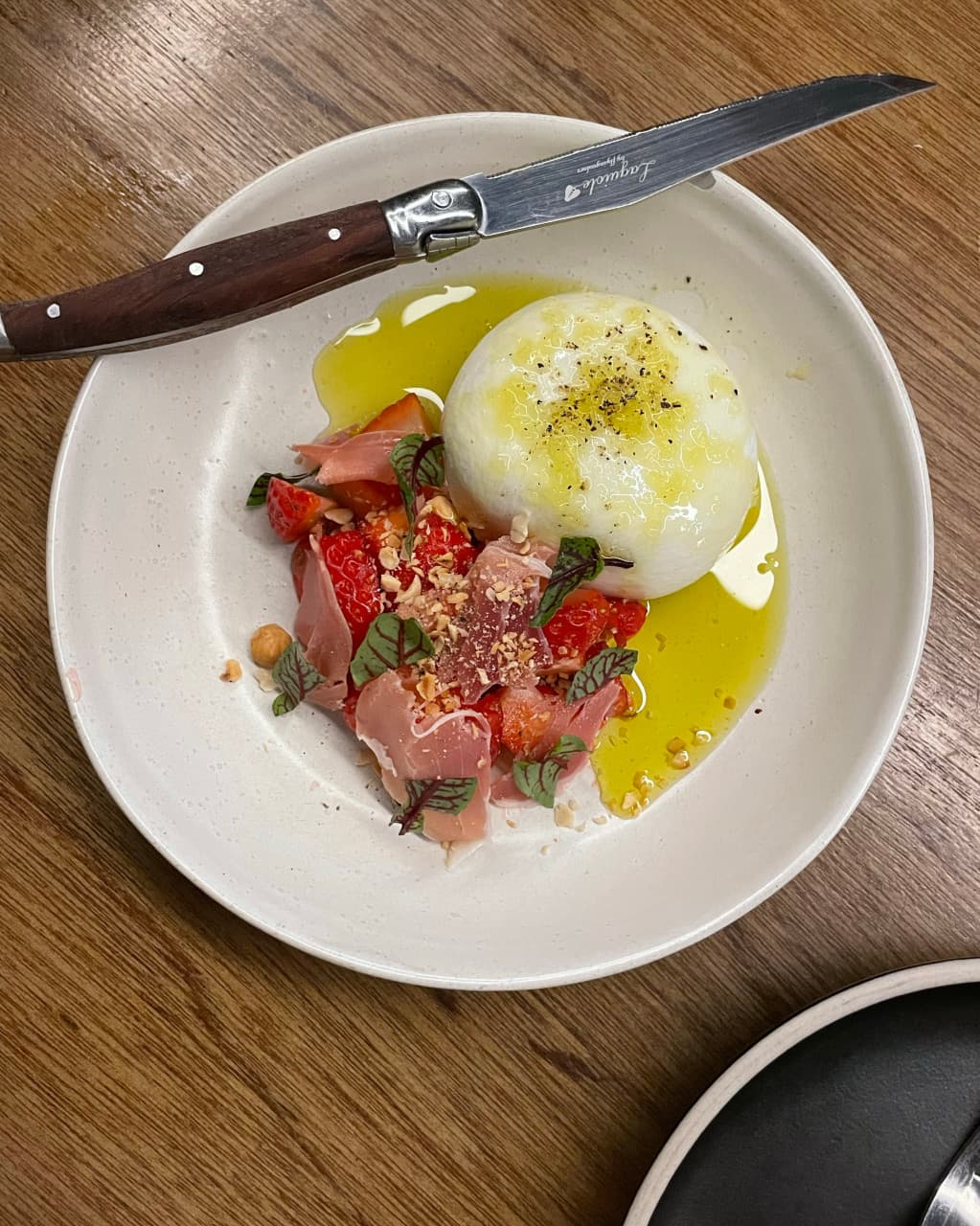 대구광역시 중구 와인바 러프 대구 동성로 혼술 테이블 위 부라타 치즈와 딸기 프로슈토. 조명 아래 올리브유가 흐르는 질감과 나무 식탁에 차려진 1인 와인 안주.