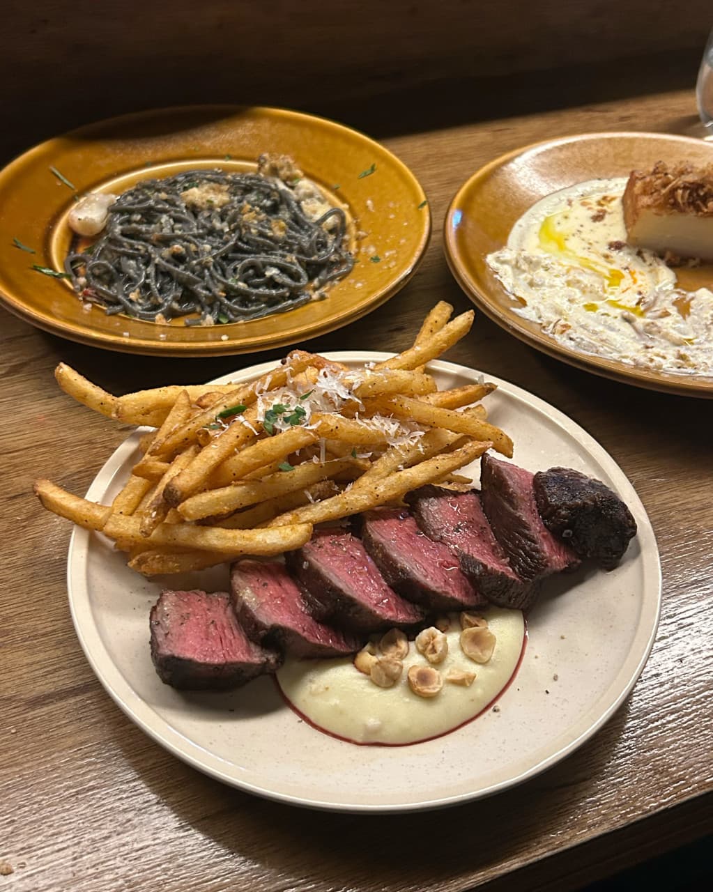 대구광역시 중구 와인바 러프 대구 동성로의 다찌석 1인 혼술. 나무 테이블 위 조명을 받은 스테이크와 감자튀김, 먹물 파스타가 차려진 모습.