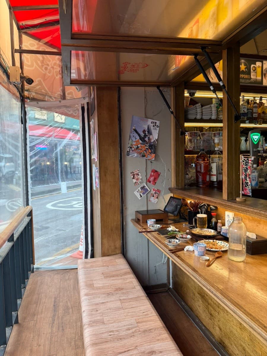 인천광역시 남동구 요리주점 하나마토 인천 구월동 다찌석에 차려진 혼술 상차림. 나무 테이블 위 생맥주와 여러 접시의 안주, 따뜻한 톤의 조명이 비치는 카운터석 뒤로 창밖 거리가 보임.