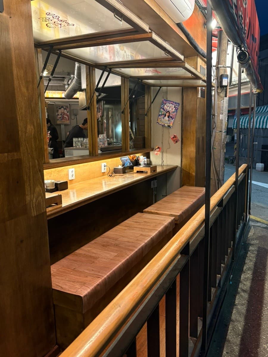 인천광역시 남동구 요리주점 하나마토 인천 구월동 야외 다찌석. 주황색 조명 아래 놓인 1인 혼술용 나무 테이블과 주문용 태블릿이 설치된 좌석 환경.