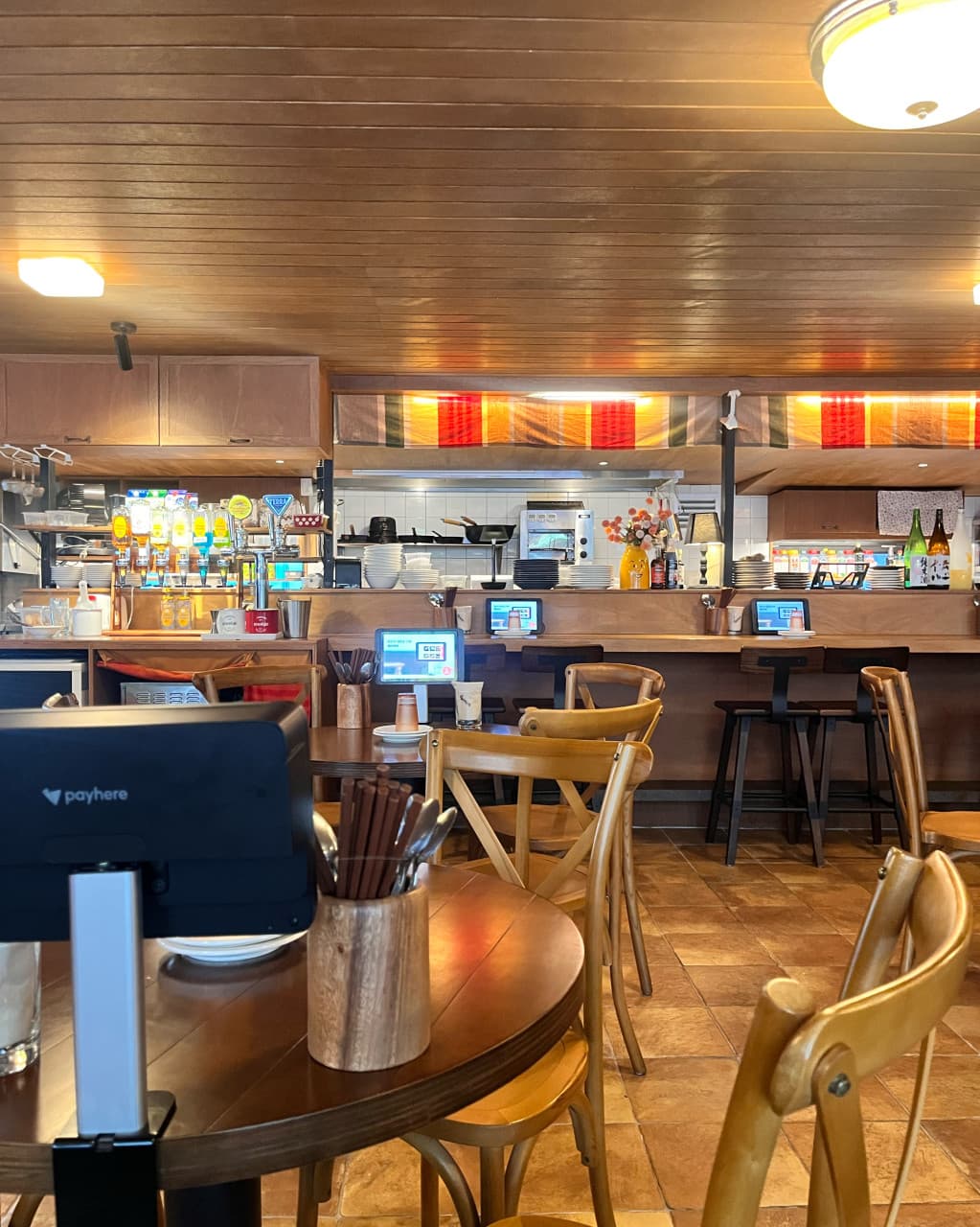 인천광역시 남동구 이자카야 쇼텐 구월점 인천 원목 테이블과 다찌석. 태블릿 메뉴판이 있는 1인 좌석과 주방 전경 조명이 혼술 상황을 보여줌.