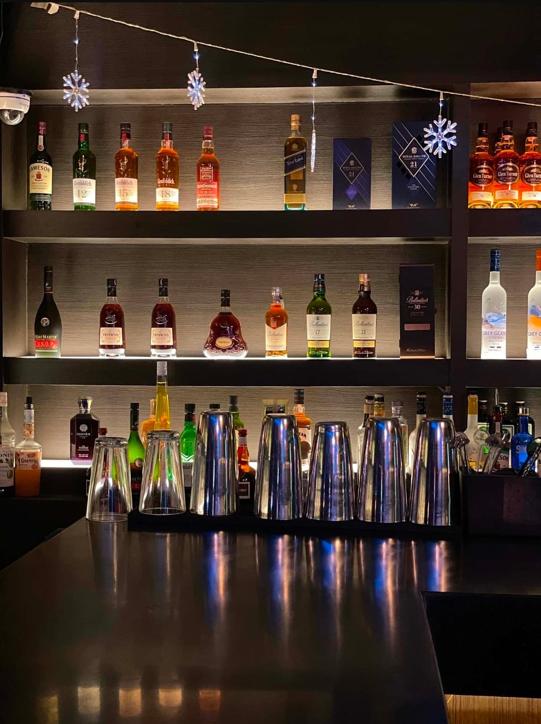 경기도 의정부시 칵테일바 크라운 - 백라이트 조명 선반 아래 진열된 위스키 병들과 다찌석 위 실버 쉐이커. 1인 혼술을 위해 정돈된 바 카운터와 금속 질감의 기물들이 배치된 내부