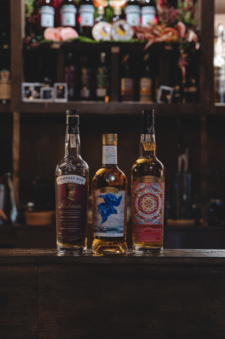 서울특별시 마포구 모던바 미티 나무 다찌석에 진열된 위스키 세 병. 어두운 배경 속 은은한 조명이 비추는 1인 카운터석에서 즐기는 혼술 상황