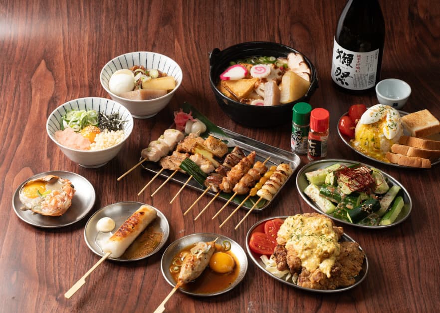 서울특별시 중구 을지로야키토리 토리노 라스베가스 이자카야 나무 테이블 위 1인 혼술 차림. 모듬 꼬치구이와 따뜻한 나베, 사케 한 병이 놓인 상황.