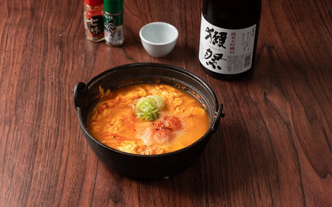 서울특별시 중구 을지로야키토리 토리노 라스베가스 이자카야 혼술. 나무 테이블 위 붉은 명란탕과 닷사이 사케, 사케 잔이 놓인 1인 다찌석 차림.