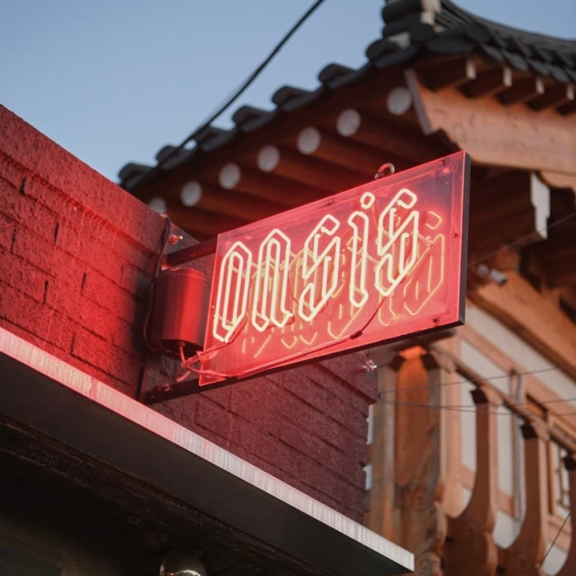 경상북도 경주시 오아시스 경주 황리단길 한옥 기와 아래 붉은 네온사인이 켜진 와인 매장 전경. 1인 혼술 다찌석으로 연결되는 입구의 붉은 벽돌과 조명 간판.