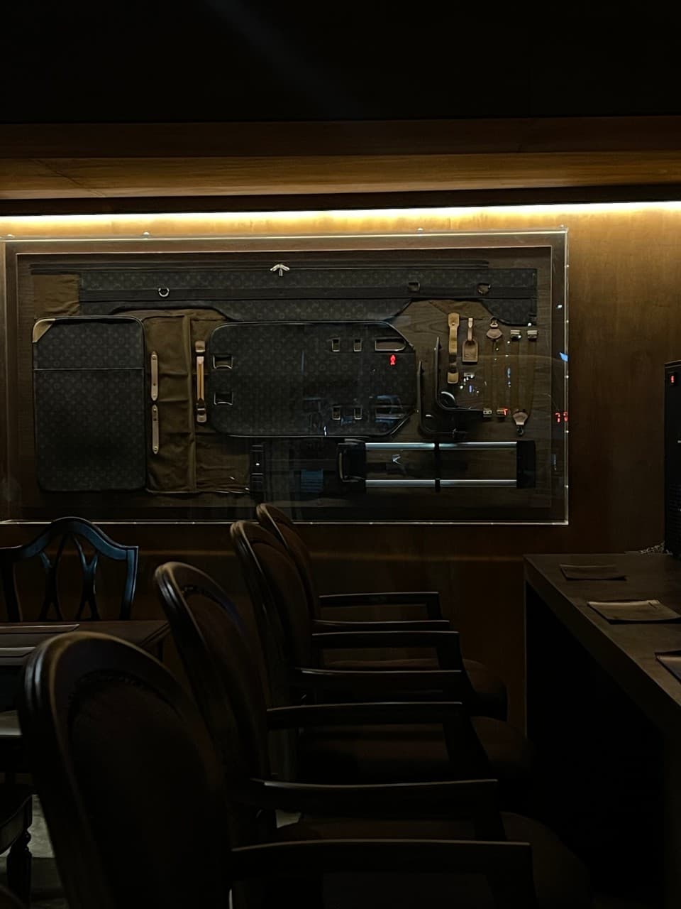 경상북도 경주시 라지백 경주 바(Bar)의 은은한 조명 아래 1인용 목재 의자가 배치된 다찌석. 벽면에 가방 부속품이 전시된 혼술 공간 상황.