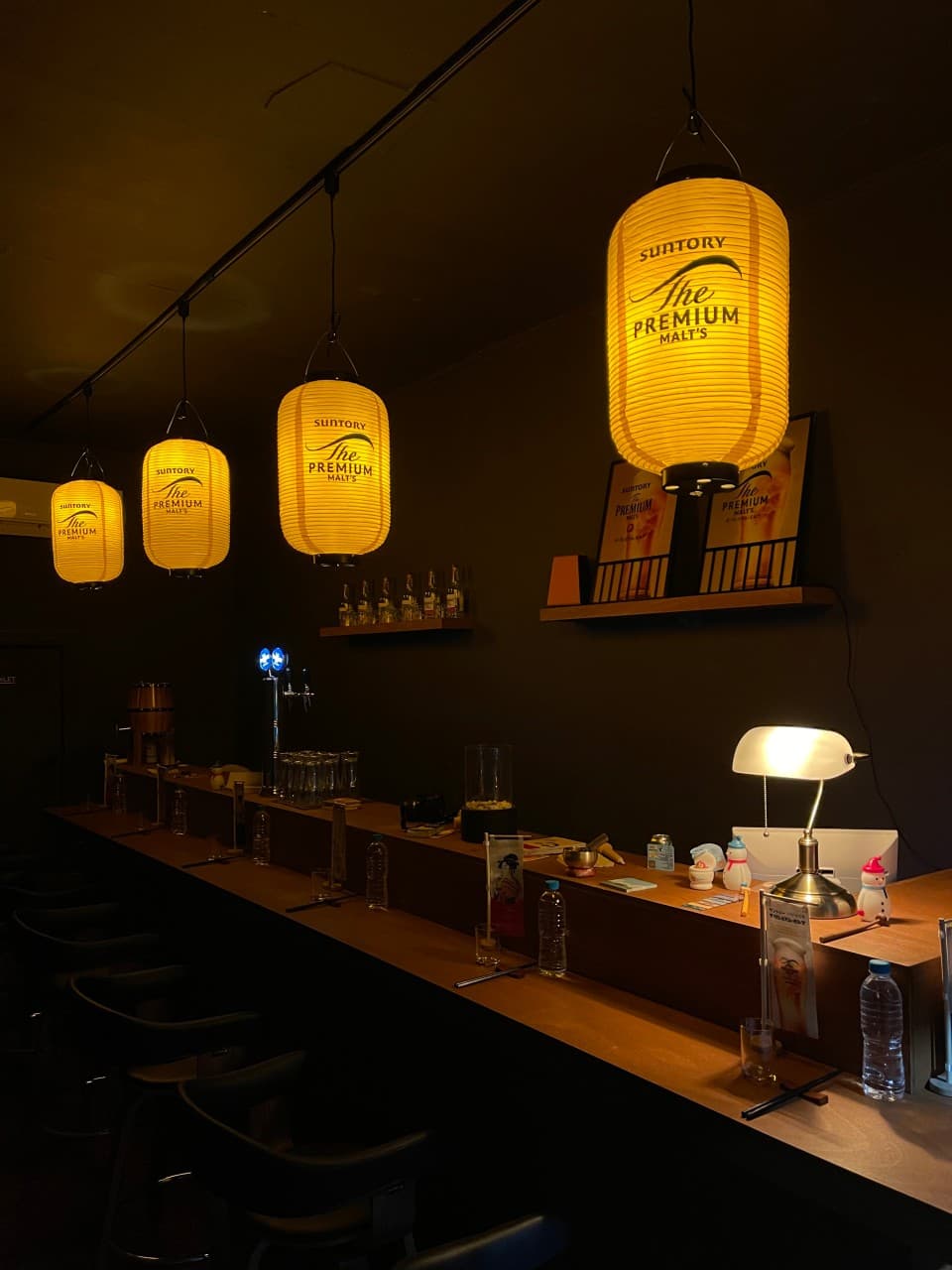 경상북도 경주시 혼술바 포 경주 바(Bar) 내부. 노란색 제등과 스탠드 조명이 비추는 목재 다찌석. 1인 혼술이 가능한 카운터 좌석에 배치된 물병과 술잔.