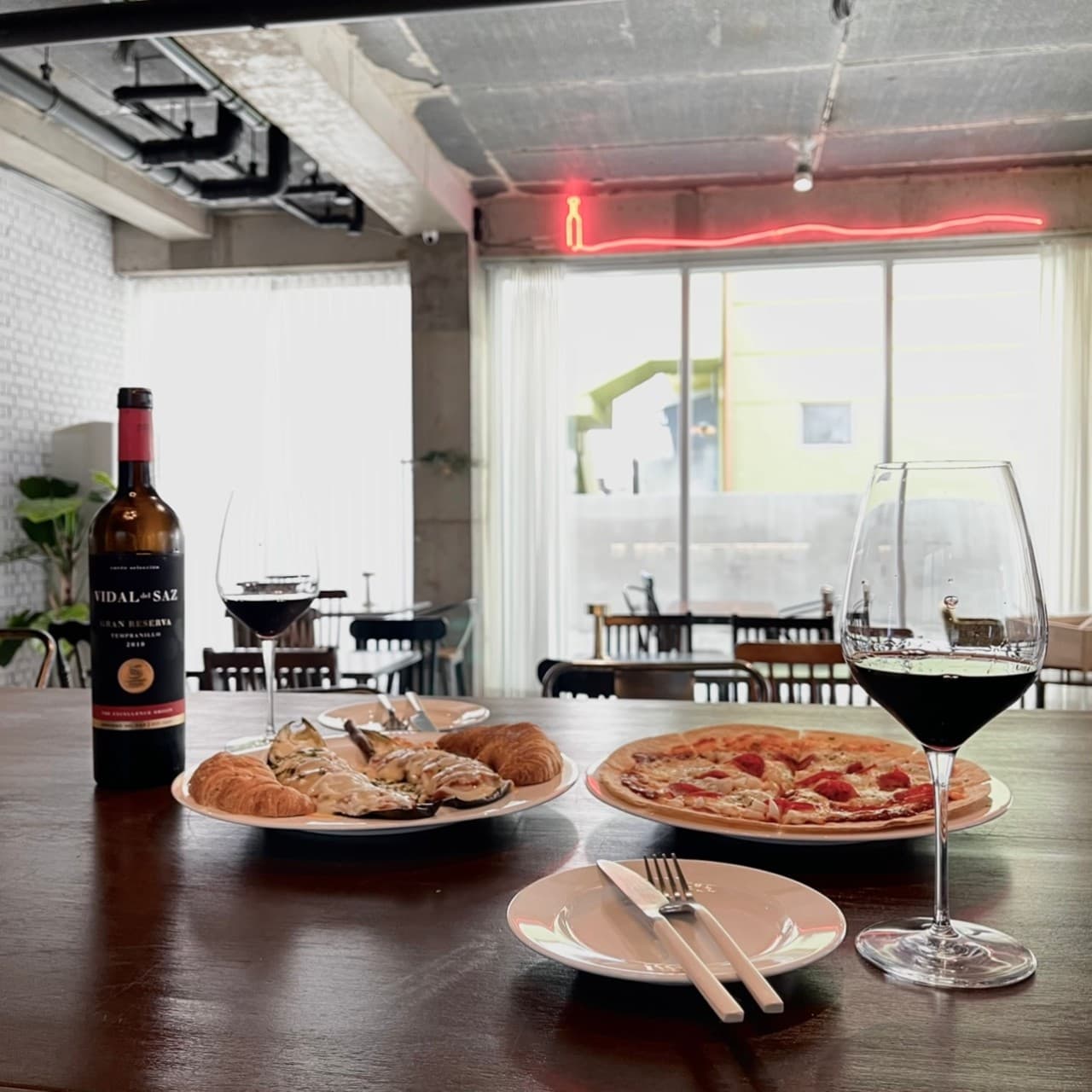 경상북도 포항시 썸씽잇 포항 와인 바 1인 혼술 상황. 목재 테이블 위 레드 와인과 피자, 치즈가 올라간 요리. 붉은색 네온 조명이 비치는 창가 다찌석 공간.