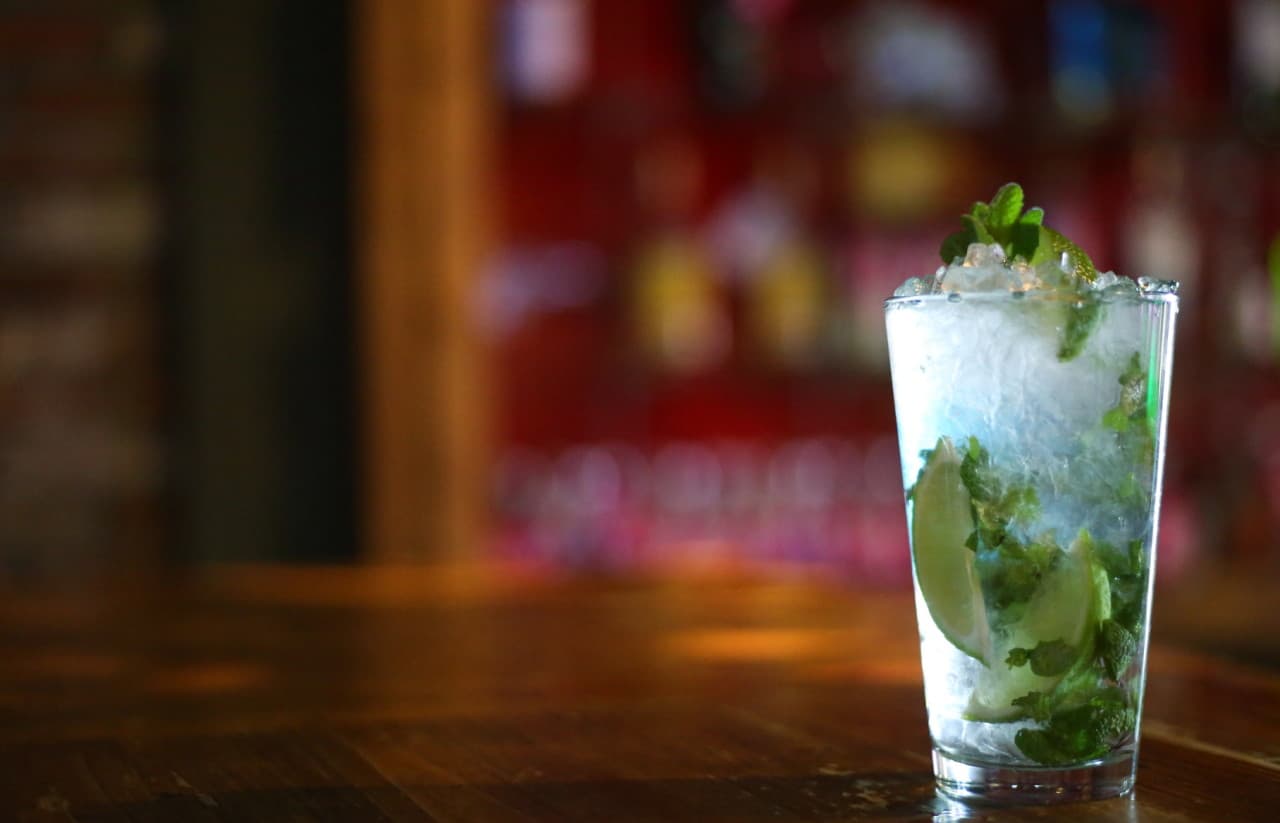 경상북도 포항시 에스플레어 포항 바(Bar) 원목 다찌석에 놓인 1인 혼술용 모히또. 잘게 부서진 얼음과 라임, 민트가 가득 담긴 투명한 잔과 은은한 조명.