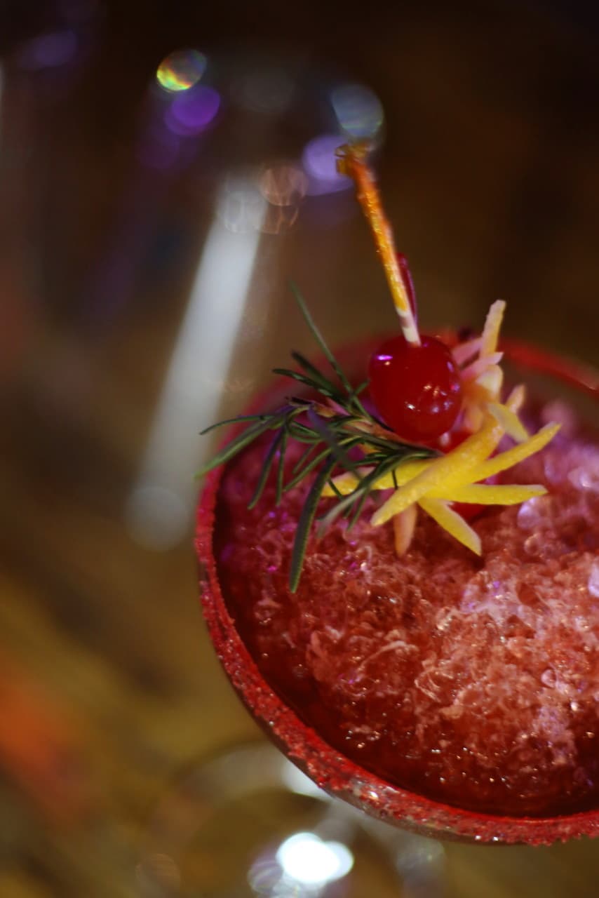 경상북도 포항시 에스플레어 포항 바(Bar) 다찌석 혼술. 조명 아래 붉은 색상의 크러쉬드 아이스 칵테일과 체리, 로즈마리 가니쉬의 질감이 돋보임.