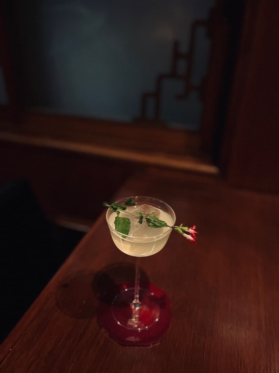 대구광역시 중구 슬로우덴 대구 바(Bar) 혼술 - 낮은 조명 아래 나무 다찌석에 놓인 꽃 장식 칵테일과 1인 좌석 상황