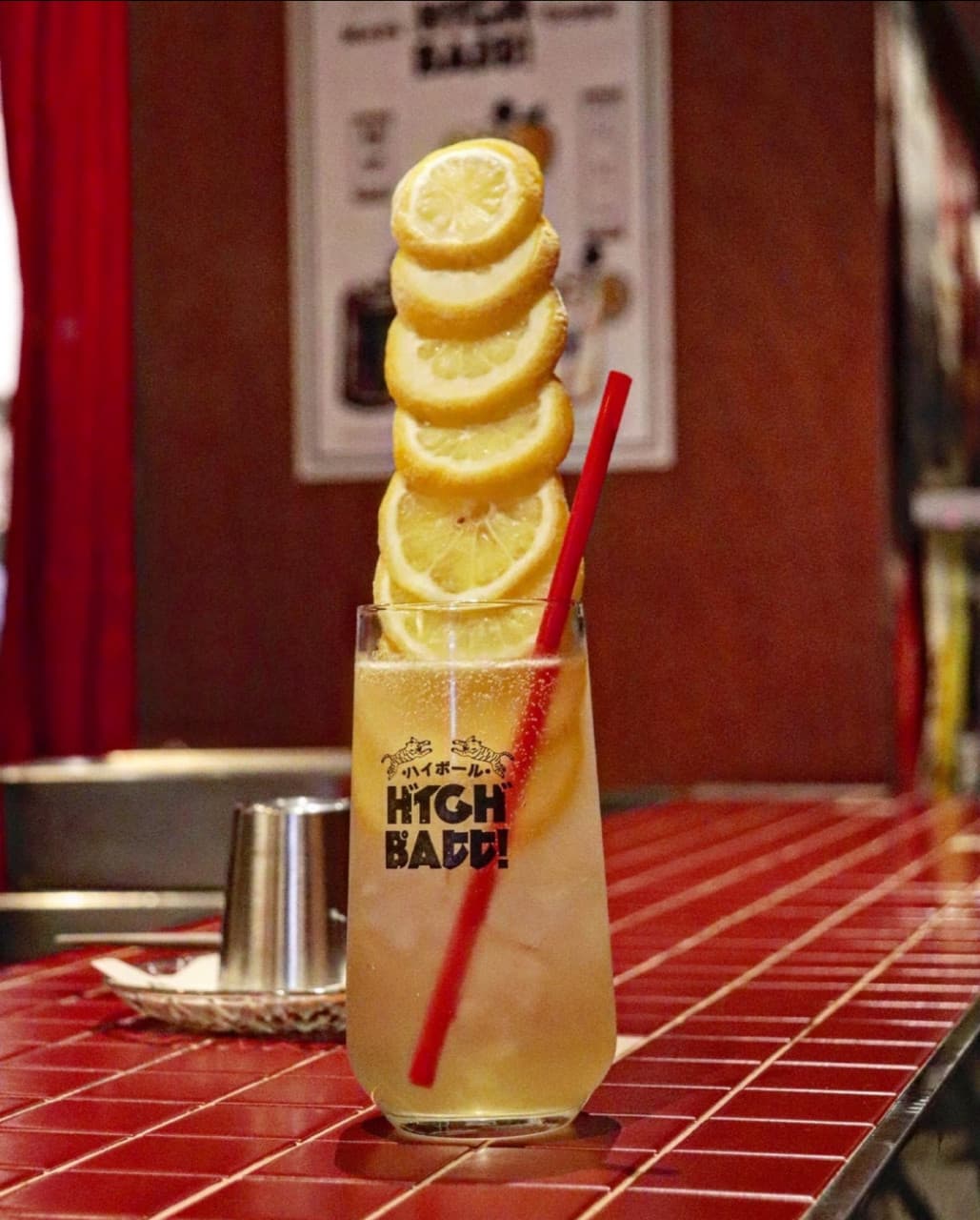 대구광역시 중구 마리타운 대구 이자카야 빨간 타일 다찌석에서 혼술로 즐기는 하이볼. 높게 쌓인 레몬 슬라이스와 빨간 빨대가 꽂힌 유리잔이 조명을 받는 상황.