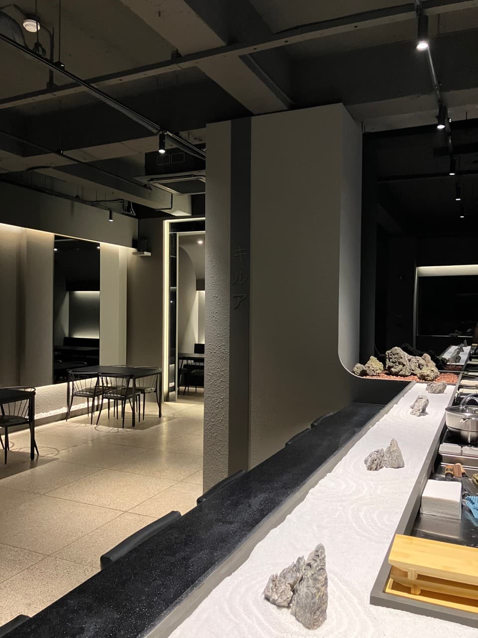 대구광역시 중구 이자카야 키르아 대구의 1인 혼술 다찌석. 흰 모래와 돌 장식이 있는 카운터와 천장 스포트라이트 조명이 비치는 내부 전경.
