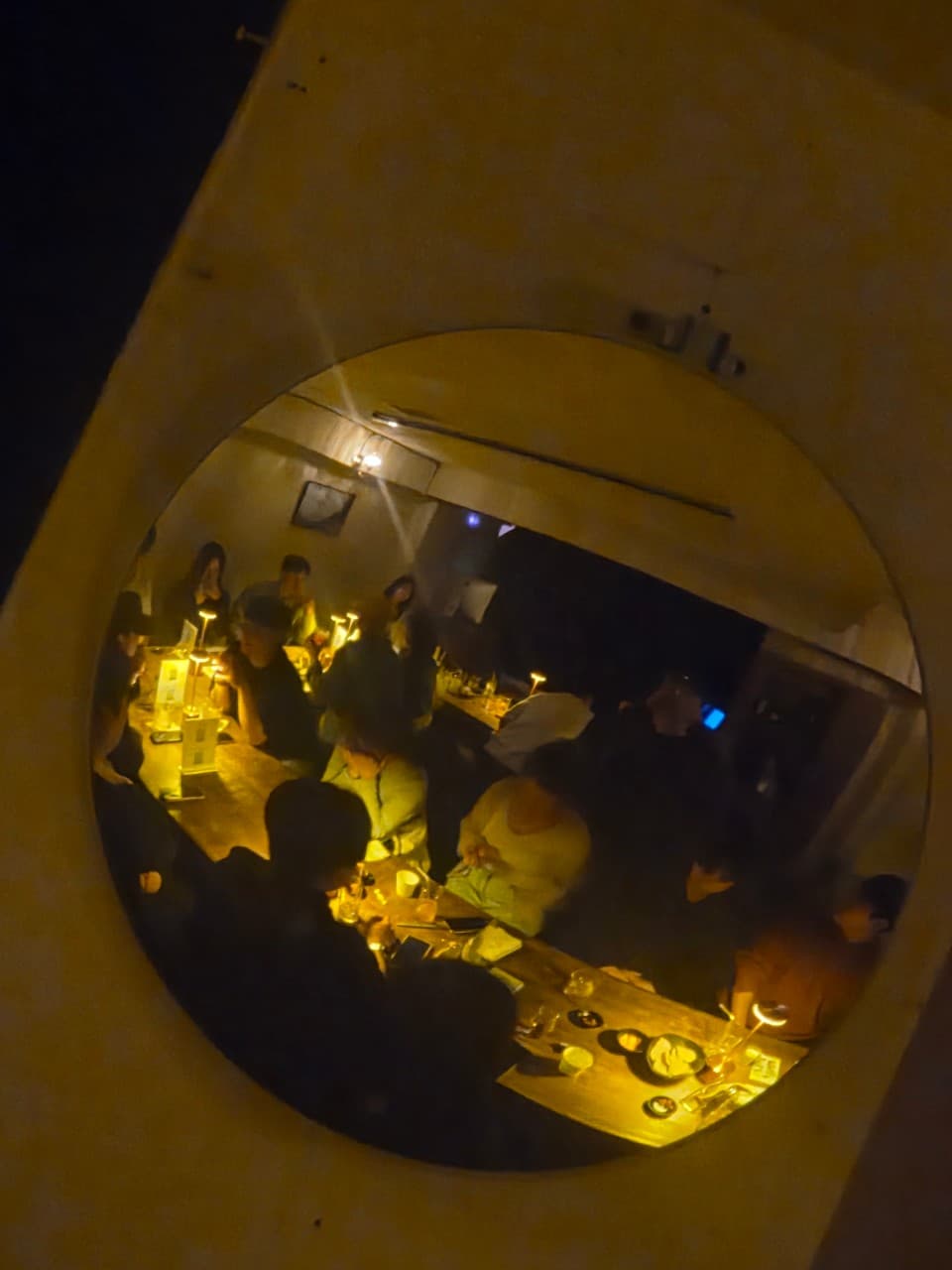 경기도 의정부시 제주도트 혼술바 의정부점 바(Bar) 다찌석. 주황색 조명이 켜진 1인 좌석에 술과 안주가 놓인 상황. 거울에 비친 어두운 실내와 테이블 위 개별 전등의 빛이 강조된 분위기.