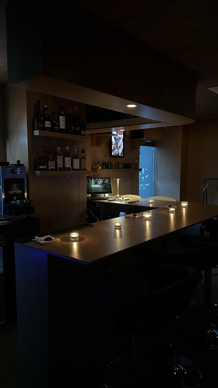 경기도 의정부시 혼술 요리주점 허술 - 촛불 조명이 켜진 다찌석과 벽면 선반에 진열된 위스키 병들이 대비를 이루는 1인 좌석 공간