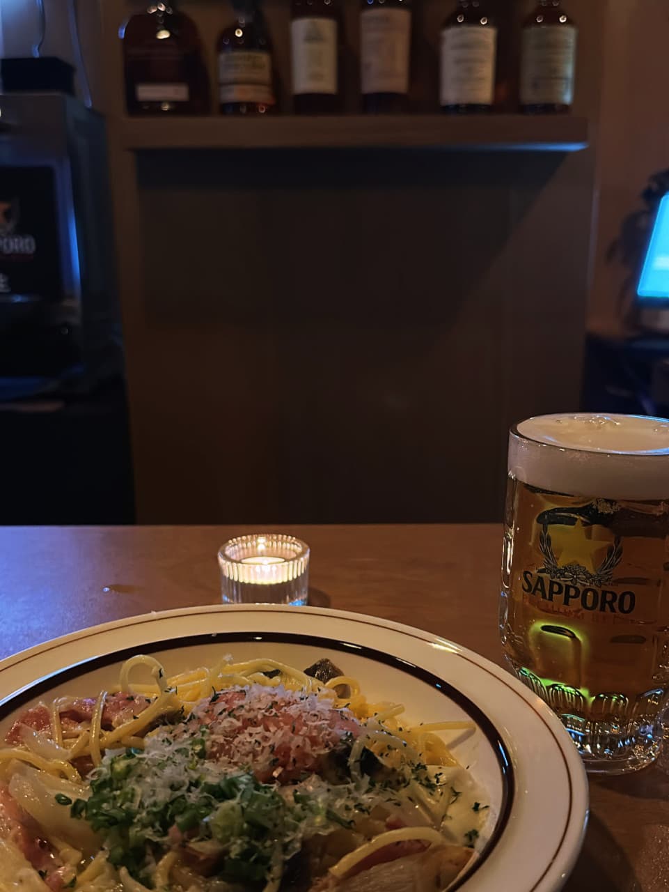 경기도 의정부시 요리주점 허술의 1인 다찌석. 촛불 조명 옆 삿포로 생맥주와 치즈 가루를 뿌린 파스타가 차려진 목제 카운터 테이블 위 혼술 상황.