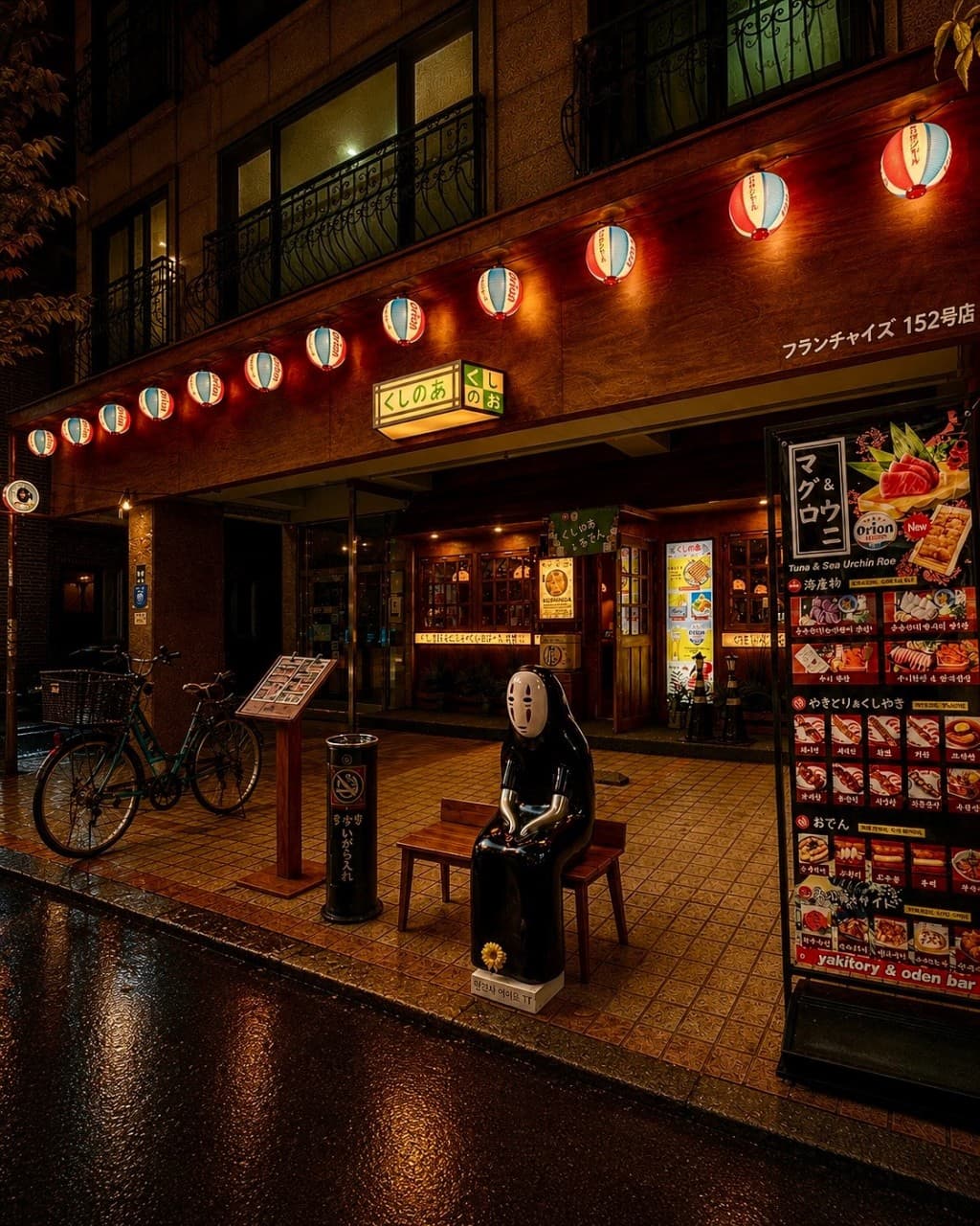 경기도 용인시 쿠시노아 보정카페거리점 경기 이자카야 입구. 붉은 제등 조명 아래 가오나시 조형물이 놓인 벤치와 혼술 전용 1인 다찌석이 마련된 목조 건물 외관.