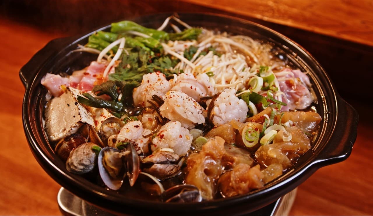 경기도 수원시 마즈비루 경기 수원 이자카야 다찌석 1인 혼술. 노란 조명 아래 대창과 조개, 고기가 담긴 전골의 질감과 나무 테이블이 배치된 상황