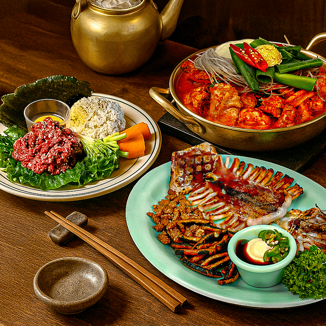 경기도 수원시 손에손잡고 광교직영점 요리주점 혼술. 조명 아래 다찌석에서 즐기는 붉은 닭볶음탕과 선홍빛 육회, 구운 오징어의 질감이 돋보이는 1인 상차림 상황.