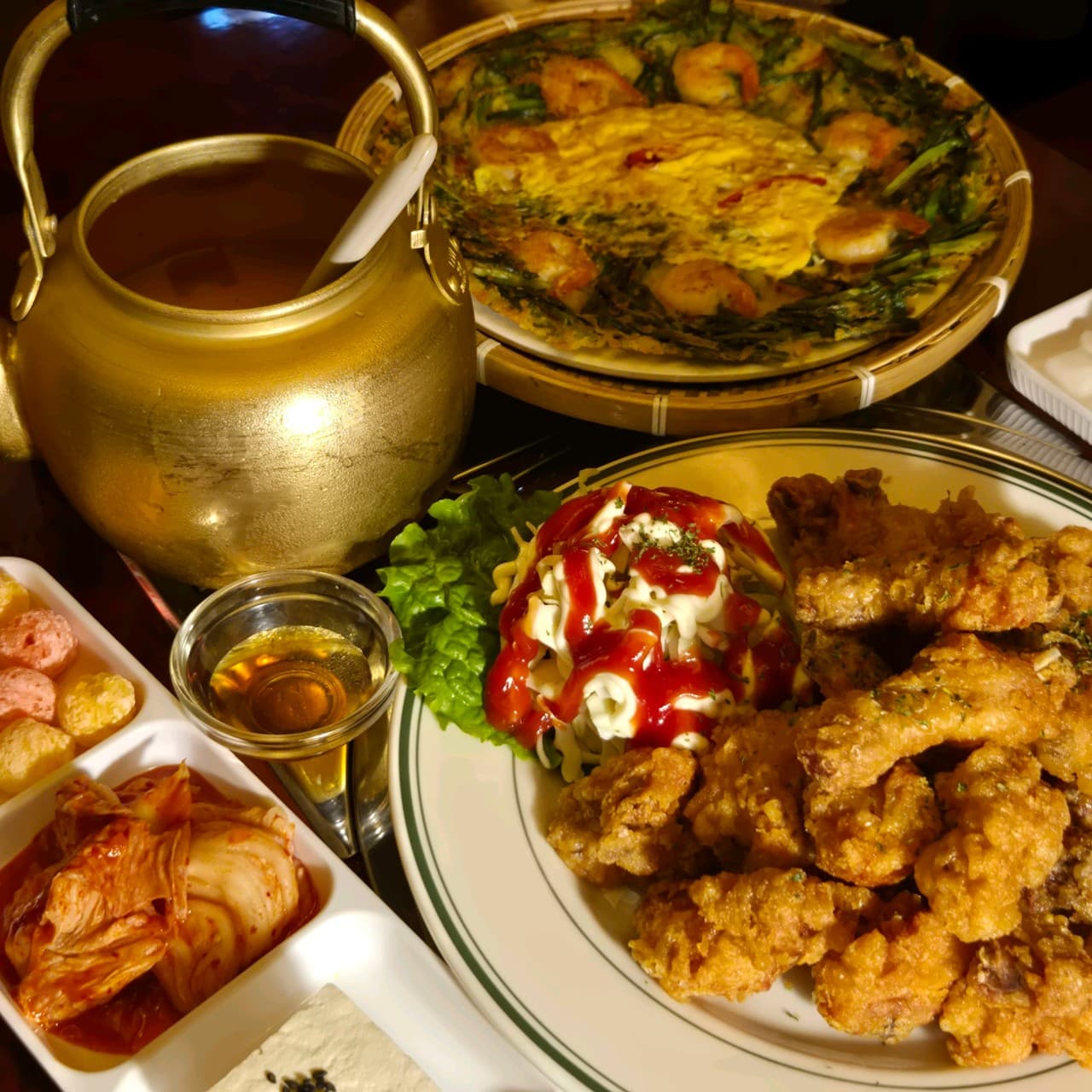 경기도 수원시 손에손잡고 광교직영점 요리주점의 노란 조명 아래 바삭한 치킨과 새우전, 황금색 주전자가 놓인 1인 다찌석 혼술 상차림