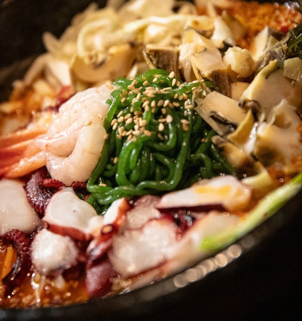 경기도 부천시 요리주점 서당의달 1인 다찌석 - 노란 조명 아래 문어와 새우, 초록색 면의 식감이 강조된 안주가 놓인 정갈한 혼술 상황