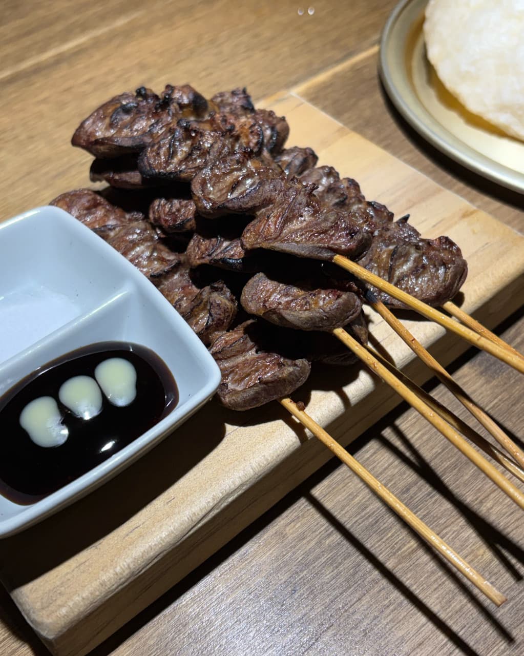 경기도 광주시 요리주점 낭만짚불구이 경안점 1인 다찌석. 짚불로 구워 결이 살아있는 염통 꼬치와 소스가 조명 아래 놓인 나무 테이블 위 혼술 차림.