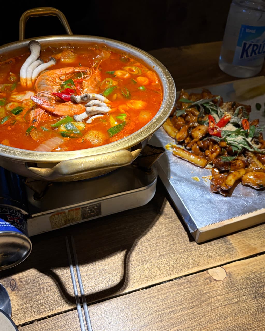 경기도 광주시 요리주점 낭만짚불구이 경안점 1인 혼술. 나무 테이블 위 붉은 새우 전골과 은박지에 담긴 짚불구이 안주에 집중된 조명.