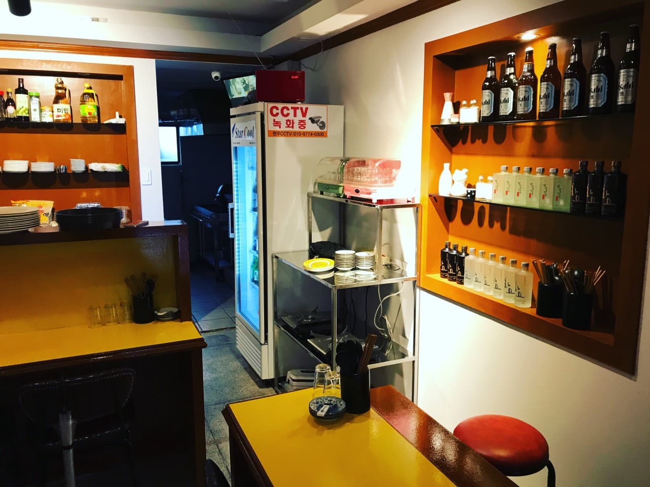 대구광역시 달서구 혼술 이자카야 성당동 소주 대구 - 노란 조명 아래 1인 다찌석과 벽면 선반에 진열된 주류병들
