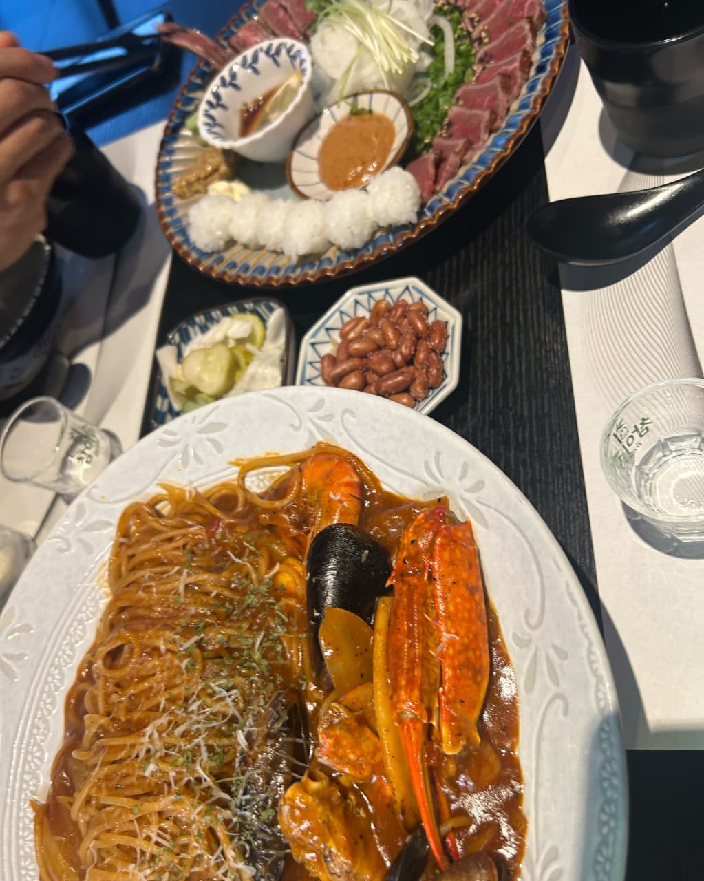 대구광역시 달서구 이자카야 대담히 신월성점 대구의 다찌석 조명 아래 차려진 1인 해산물 파스타와 타타키. 혼술 메뉴의 질감이 돋보이는 테이블 위 상황.