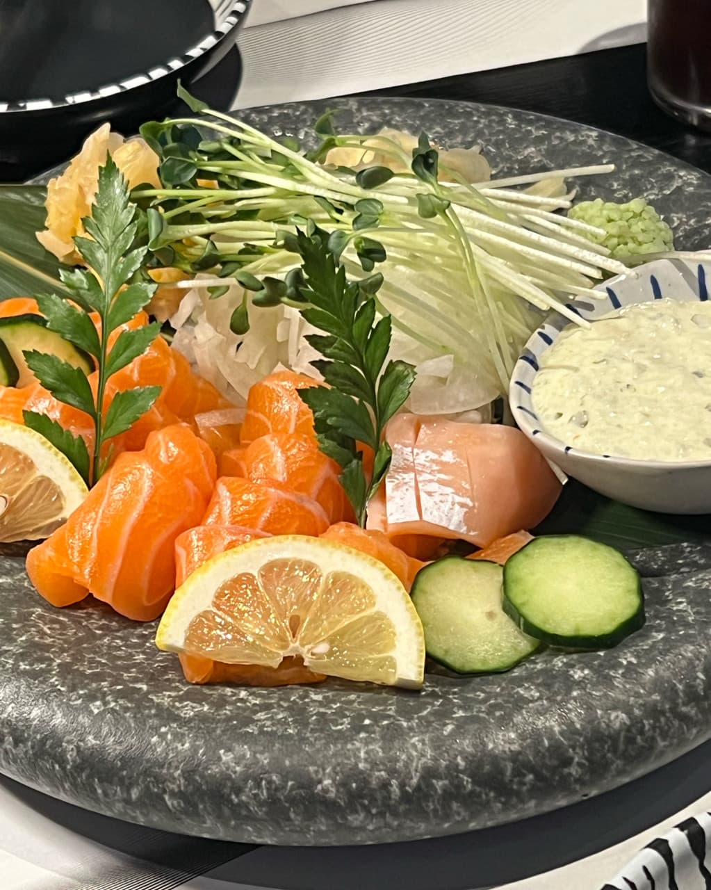 대구광역시 달서구 이자카야 대담히 신월성점 대구의 다찌석 조명 아래 차려진 1인 연어 사시미. 레몬과 무순을 곁들인 선홍빛 연어 질감이 강조된 혼술 차림.