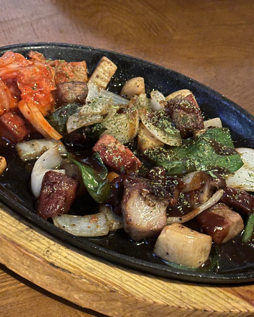 대구광역시 중구 헬로외국포차 대구 맥주 호프의 조명 아래 1인 다찌석과 김치 고기 볶음 철판 요리. 나무 테이블 위에서 혼술하며 즐기는 안주의 질감과 구성.