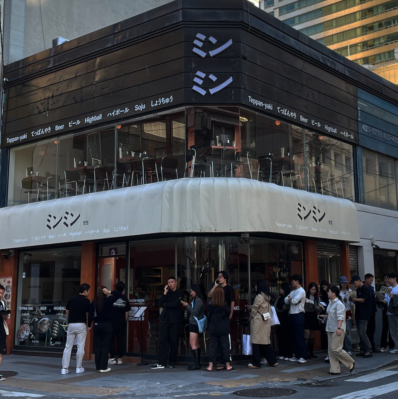 대구광역시 중구 맴맴 대구교동점 요리주점 외관으로 통유리창 너머 1인 다찌석과 조명이 보이며 입구에 대기하는 사람들로 붐비는 혼술 전문점의 모습